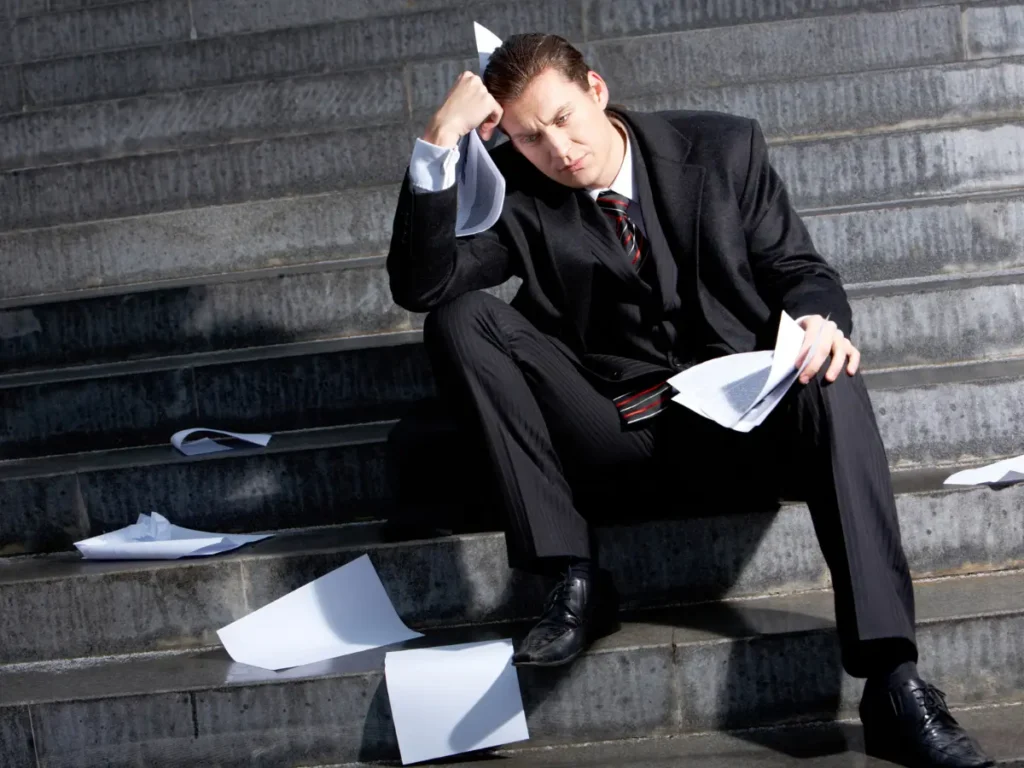 A DUI offender sits on the stairs looking distraught with case documents sprawled around him.