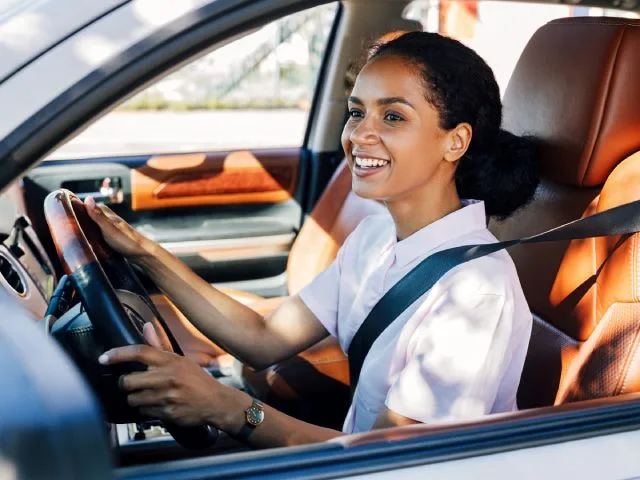 A woman smiles while driving after her license is reinstated.
