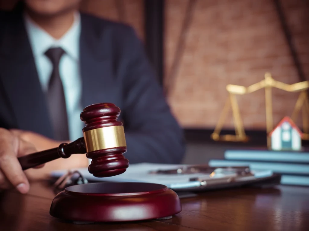 Judge holding a gavel at a courtroom desk with legal documents.