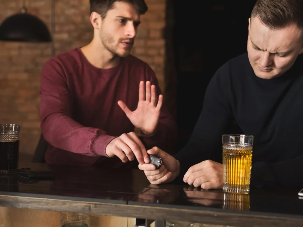 A man takes the car keys of his drunk friend.