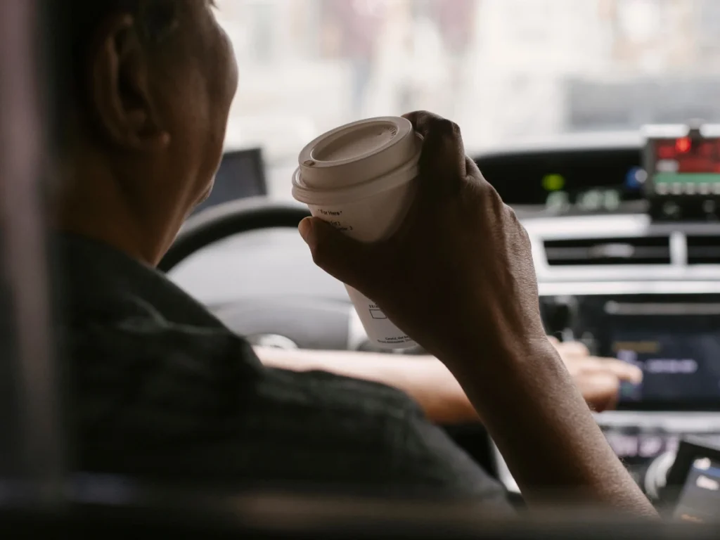 A man drinks coffee inside his car.