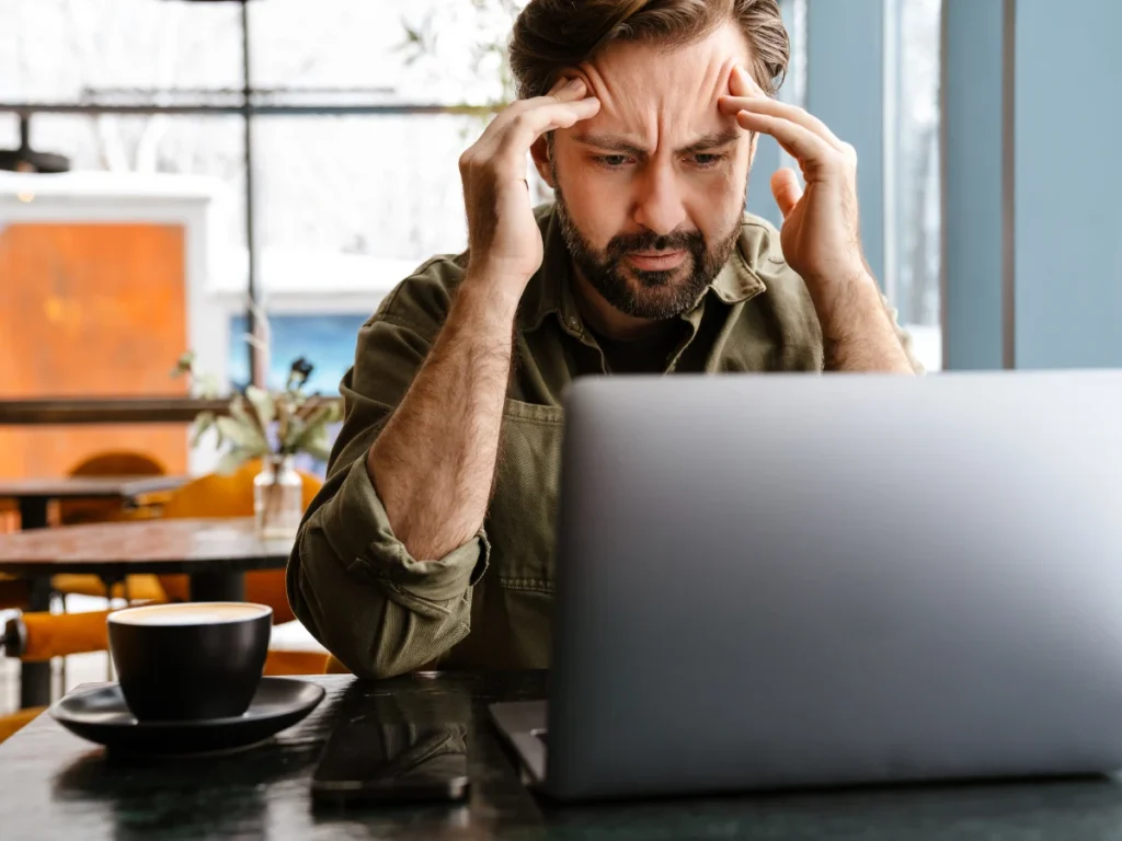 A man rubs his temples in worry while checking his DUI record online.